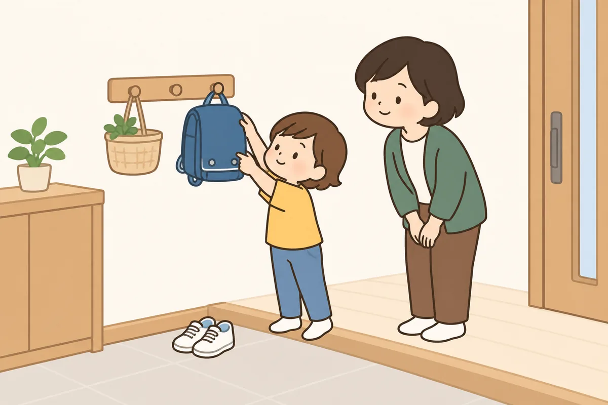 玄関で、子どもがかばんをフックに掛けようとしている。