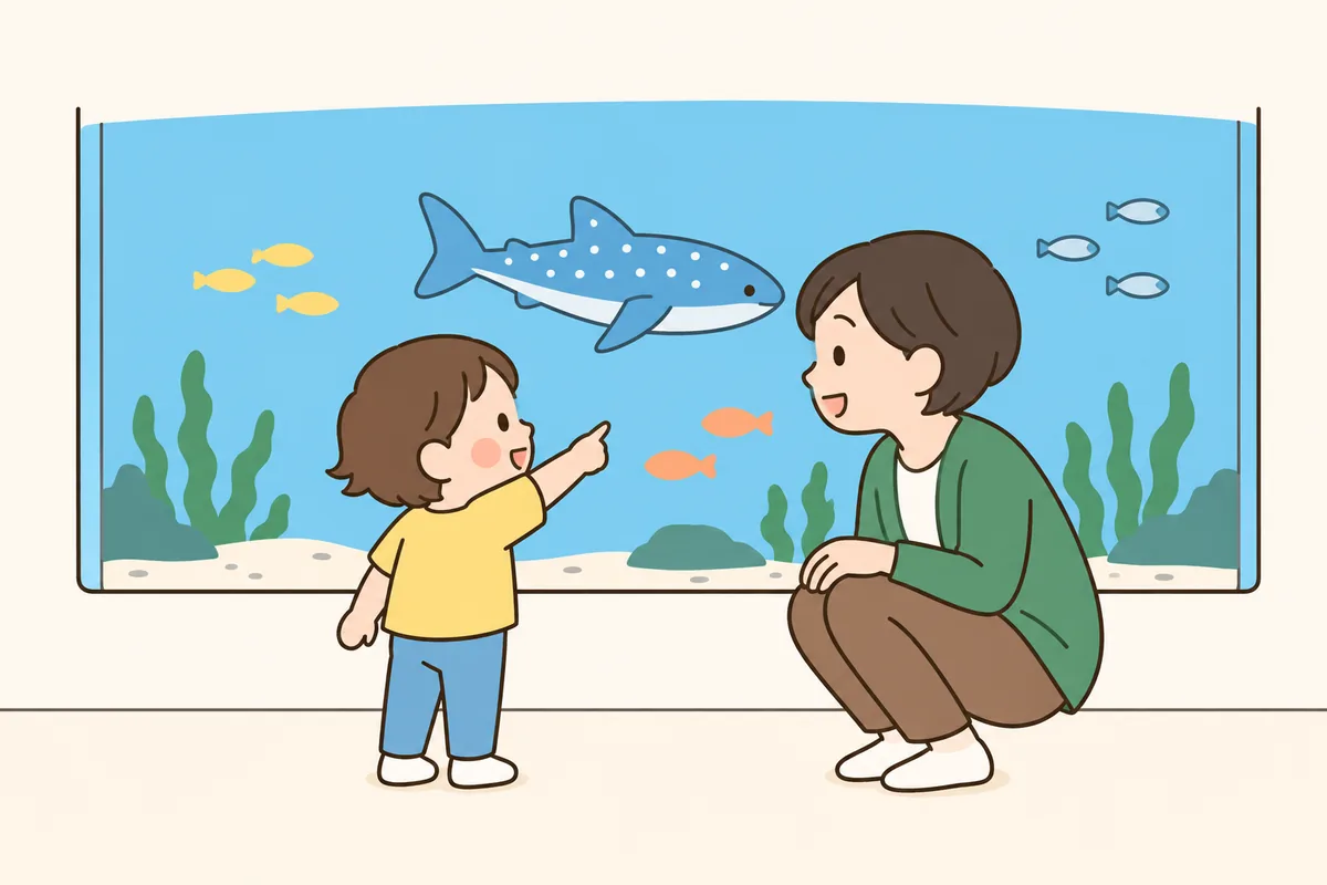 水族館の水槽の前で、子どもが指さした魚を見ながら大人が話し返している